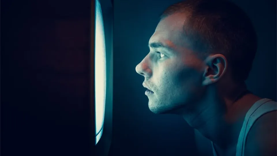 Face lit blue by a screen