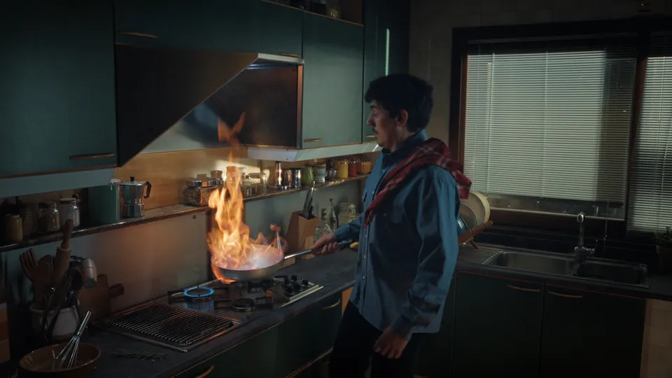 A pan flares up in a dark kitchen