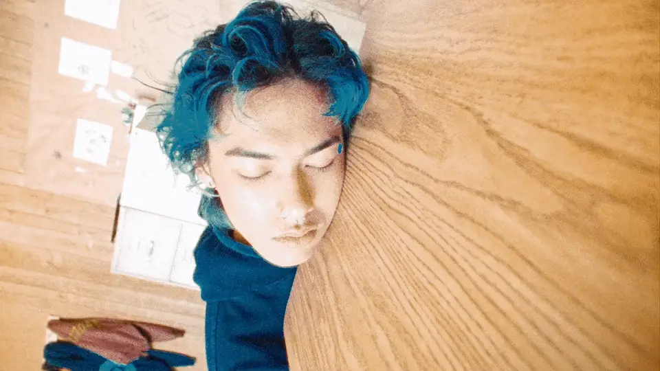 Head on the table, eyes open, he sits up
